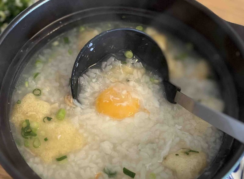 油揚げや月見卵が入った中華粥。湯気をたてながら土鍋に入っている
